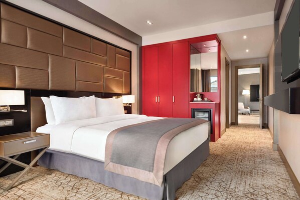 Una habitación de hotel moderna con una cama grande, un armario rojo, un escritorio pequeño y una televisión.