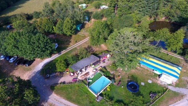 An aerial view of a property with a swimming pool, a large blue and yellow building, and several parked cars. - Camping des Etoiles - Mobil-Home (Najac)