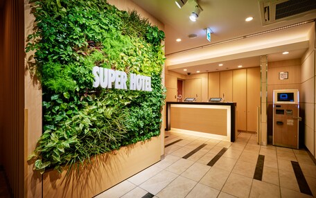 A reception area with a green wall, a reception desk, and a digital screen.