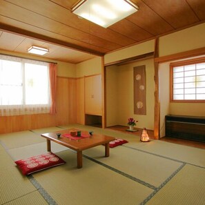 Une pièce de style japonais traditionnel, avec un sol recouvert de tatamis, une table basse, des portes coulissantes et un paravent en papier de riz (shoji).