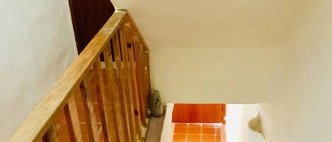 A wooden staircase with a handrail, leading to a landing with a tiled floor.
