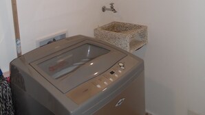A compact laundry room with a built-in washer and dryer, a small sink, and a towel rack. - Studio in Laureles (Medellín)