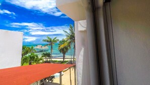 A balcony with a view of the ocean, palm trees, and a beach. - Unit #2 Beautiful Suite Chill beach front (Cancun)