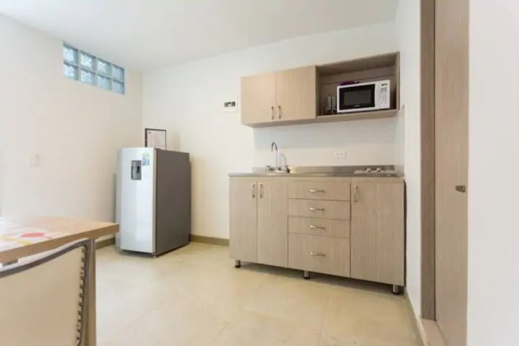 A small kitchen with a refrigerator, microwave, and wooden cabinets.
