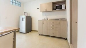 A small kitchen with a refrigerator, microwave, and wooden cabinets.
