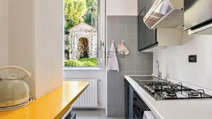 Eine moderne Küche mit Gasherd, Wasserkocher, einem Fenster mit Blick auf einen Garten und ein Gebäude sowie einem Handtuchhalter.