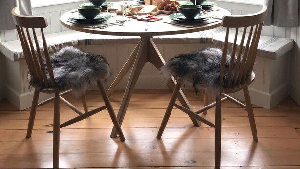 Uma janela panorâmica com uma mesa posta para dois, com comida e copos de vinho.
