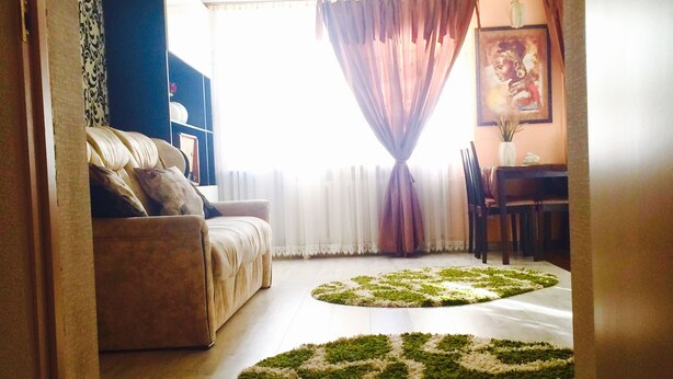 A living room with a sofa, a dining table, and two rugs.