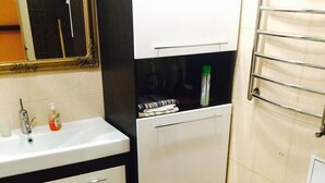 A small bathroom with a sink, mirror, toilet, and a towel rack.