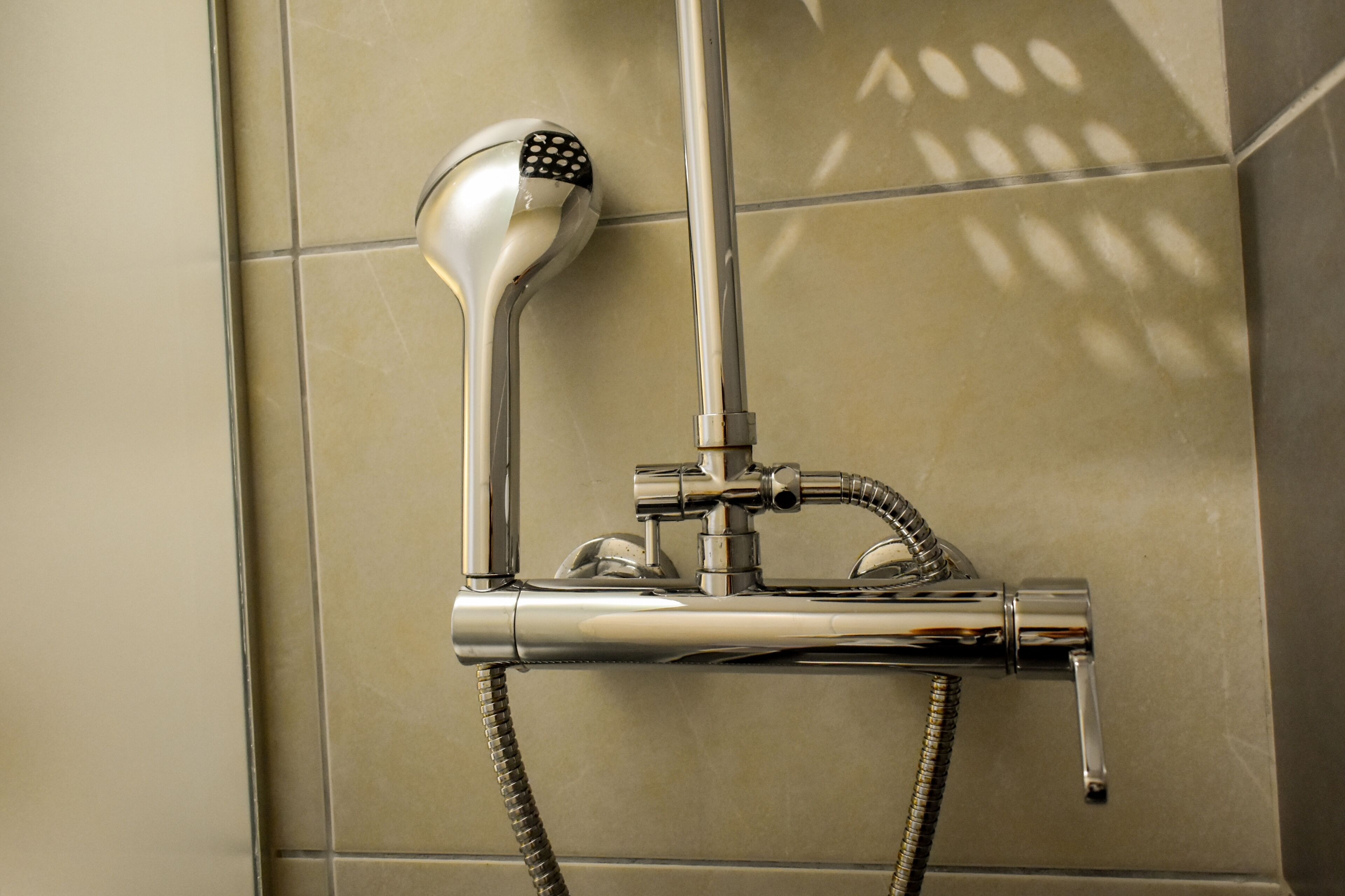 Una ducha con cabezal de ducha manual y manguera flexible.