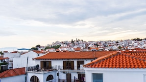 A coastal town with terracotta-tiled rooftops, white buildings, and a hilly backdrop.