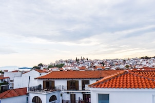 Un pueblo costero con tejados de tejas color terracota, edificios blancos y un paisaje montañoso de fondo.