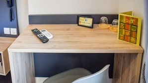 A small wooden table with a remote control, a small digital clock, and a menu card.