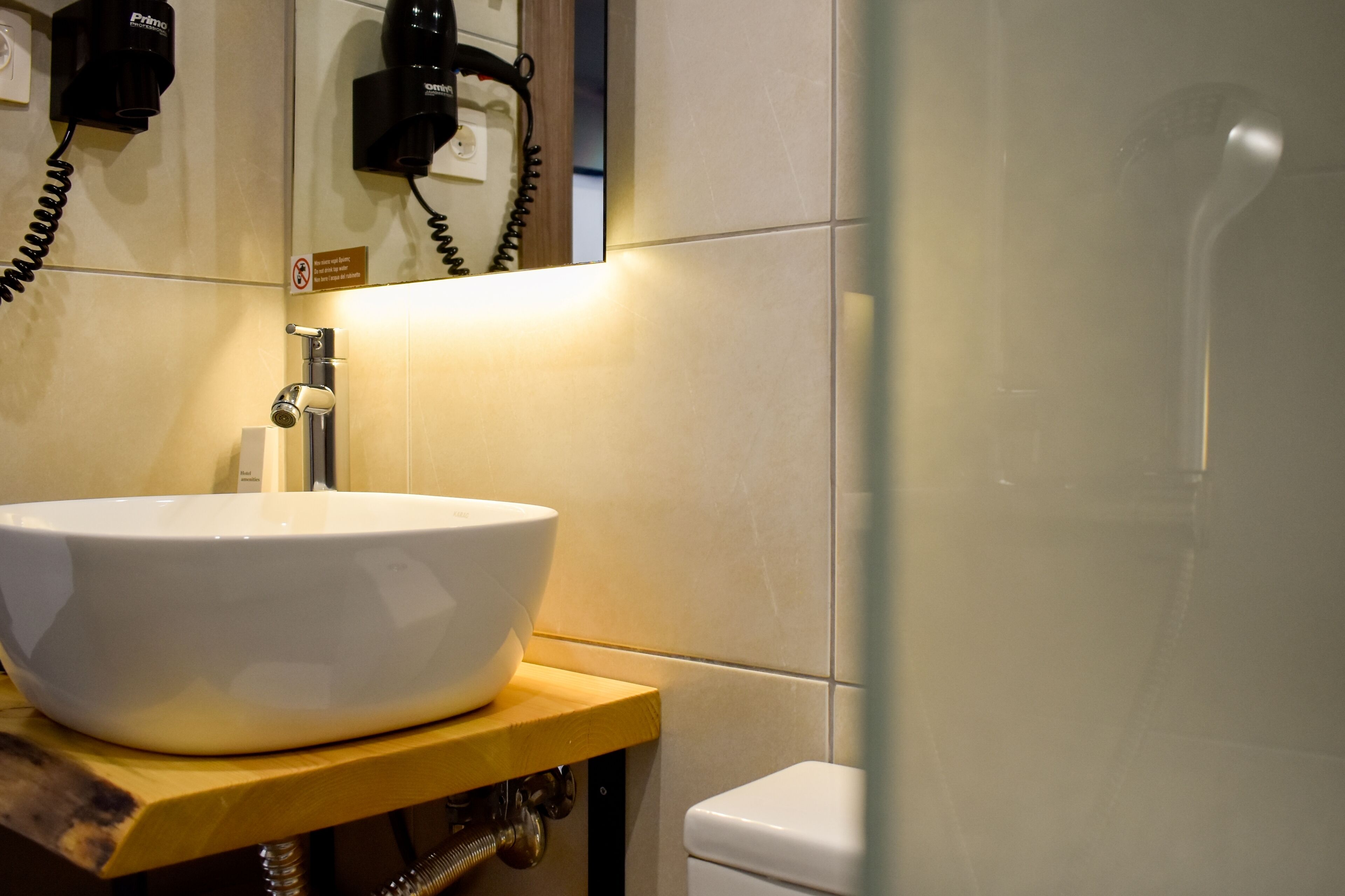 A bathroom with a white sink on a wooden countertop, a mirror, and a shower area.
