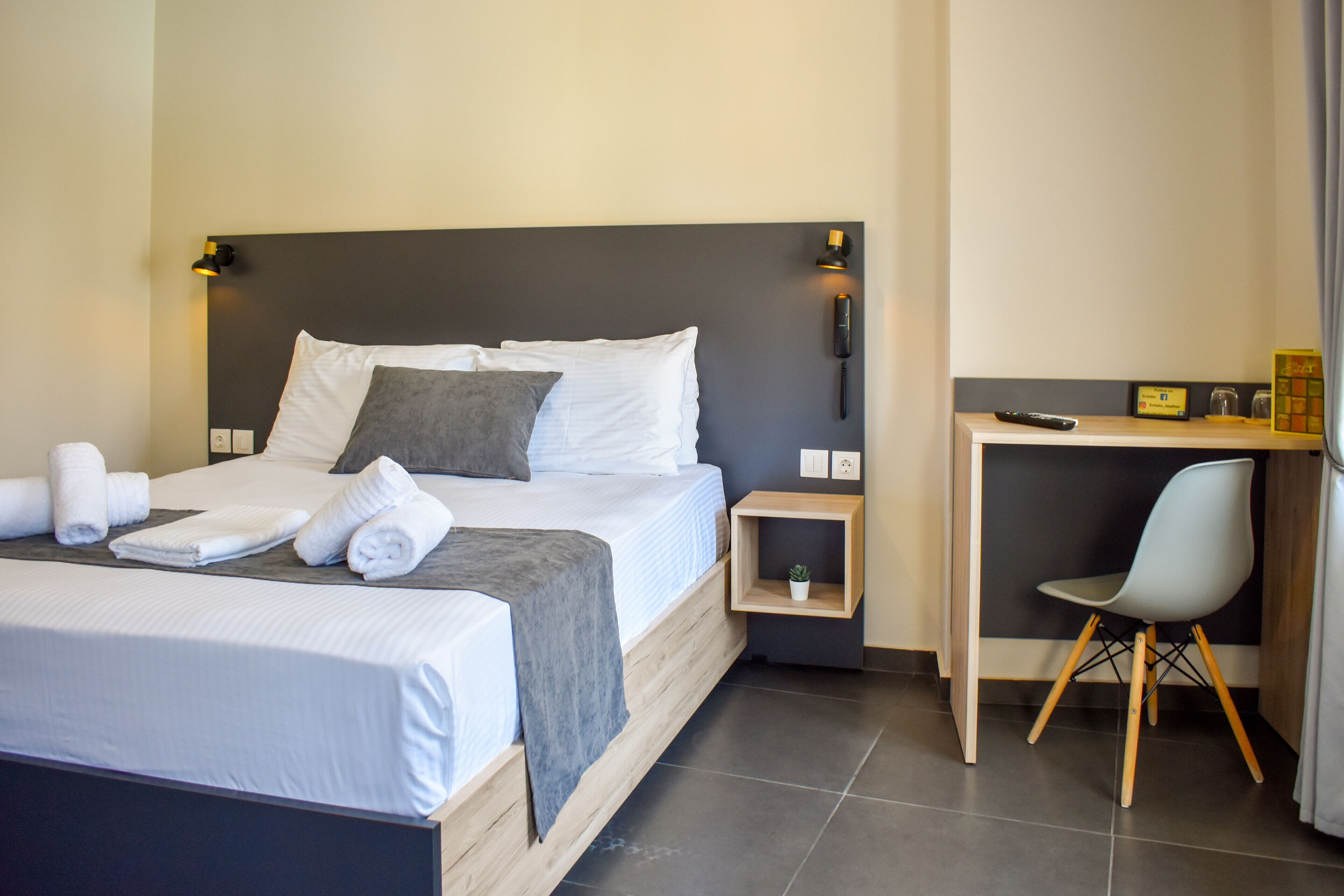 A hotel room with a bed, bedside tables, a desk, and a chair.