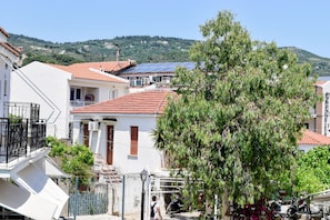 A residential area with houses featuring red-tiled roofs, a tree, and solar panels on one roof. - Entelia (Skiathos)