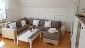 Ein modernes Wohnzimmer mit einem Ecksofa, einem weißen Couchtisch und einer Vitrine.