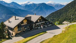 Un albergue de montaña con restaurante y terraza, rodeado de montañas.