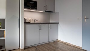 Una cocina moderna con armarios blancos, un microondas y un lavamanos.