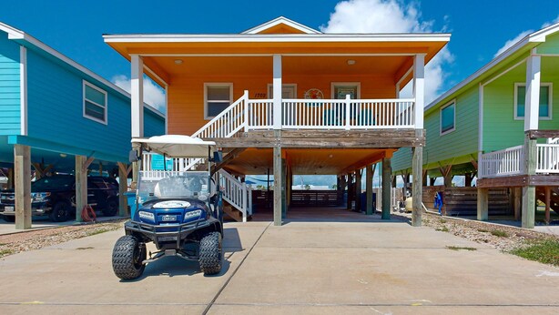 A two-story house with a balcony, a covered porch, and a golf cart parked in front. - FC1702 Private Heated  Pool, Room for Boat Parking, Golf Cart Included (Port Aransas)
