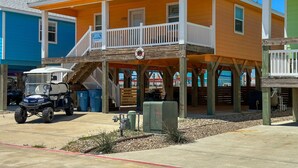 A two-story building with a balcony, a golf cart, and a lifeguard stand. - FC1702 Private Heated  Pool, Room for Boat Parking, Golf Cart Included (Port Aransas)