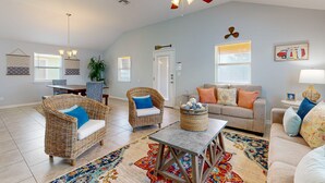 A spacious living room with a high ceiling fan, wicker furniture, a gray sofa, and colorful rugs. - FC1702 Private Heated  Pool, Room for Boat Parking, Golf Cart Included (Port Aransas)