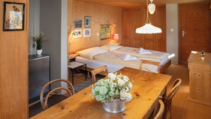 A wooden room with a bed, a table with chairs, a small cabinet, and a wall with framed pictures. - Jungfrau a d Ledi by Interhome (Wengen)