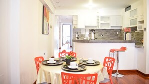 A dining area with a round table set for four, surrounded by red chairs, and a kitchen area with white cabinets and a microwave.