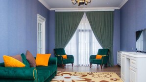 A living room with a green sofa, two green armchairs, a white cabinet, and a chandelier. - Gachresh Forest Resort (Quba)