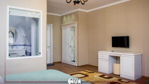 A bedroom with a large bed, a vanity with a mirror, a wardrobe, a desk, and a television. - Gachresh Forest Resort (Quba)