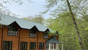 A wooden cabin with a stone foundation, large windows, and a small porch. - Gachresh Forest Resort (Quba)