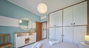 A bedroom with a bed, a bedside table, a mirror, a wardrobe, and a hanging light fixture. - Villetta Arcobaleno - with lake view and pool (Bardolino)