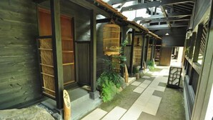 A traditional wooden building with tatami mat flooring, a stone lantern, and a wooden door. - Futarishizuka (Kirishima)