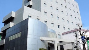 A multi-story building with a modern architectural design, featuring a prominent entrance with a covered area and a visible sign.