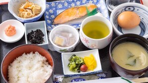 A tray with various Japanese dishes including rice, soup, and a fish.