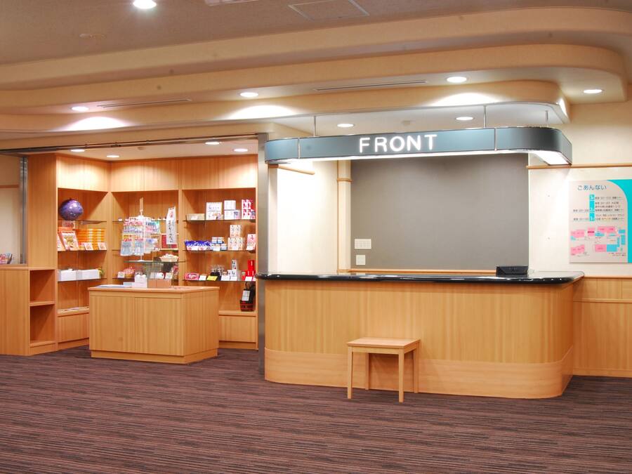 A reception area with a wooden counter, a small table, and a bulletin board with notices.