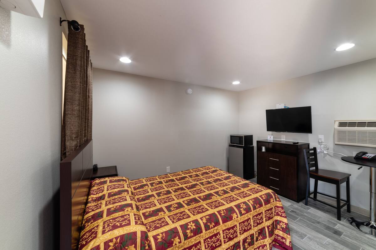 A bedroom with a bed, a desk, a chair, a television, and a wardrobe.