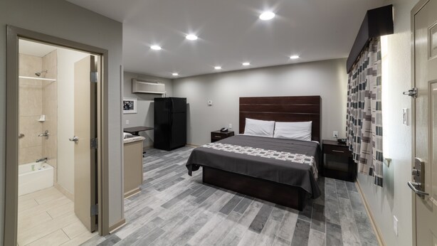 Une chambre moderne avec un grand lit, un dressing, une salle de bain avec douche et un petit coin bureau.