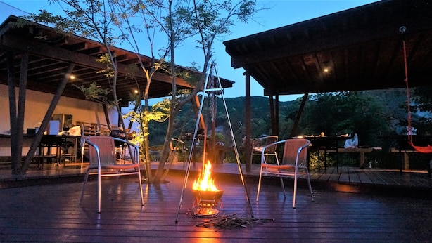 An outdoor patio with a fire pit, chairs, and a covered area with tables and chairs. - Amagi Onsen Zen no Yu (Kawazu)