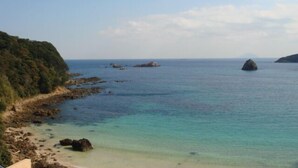 A coastal landscape with clear water, rocky shoreline, and distant landforms. - Amagi Onsen Zen no Yu (Kawazu)