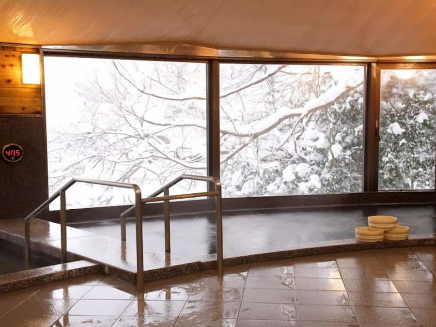Una sauna con amplios ventanales, interior de madera y suelo de baldosas.