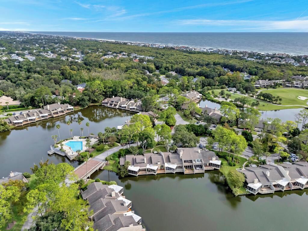 A residential area with houses by a lake, a swimming pool, and a golf course in the background.