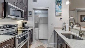 A modern kitchen with stainless steel appliances, a white refrigerator, and a sink. - Fun in the Sun - Coastal studio w/ pool access (Ponte Vedra Beach)