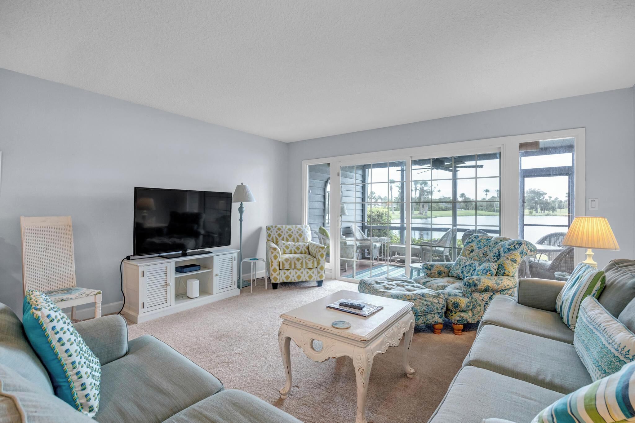 A living room with a flat-screen TV, a sofa, a coffee table, and a chair.