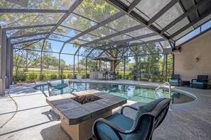 A covered outdoor swimming pool with seating and a fire pit, surrounded by a metal frame and glass panels. - Club Views - Pet-friendly 5BR w/ pool & BBQ patio (Ponte Vedra Beach)
