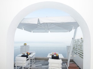 A terrace with white tables and chairs, white umbrellas, and a view of the sea. - Villa Orleans (Amalfi)