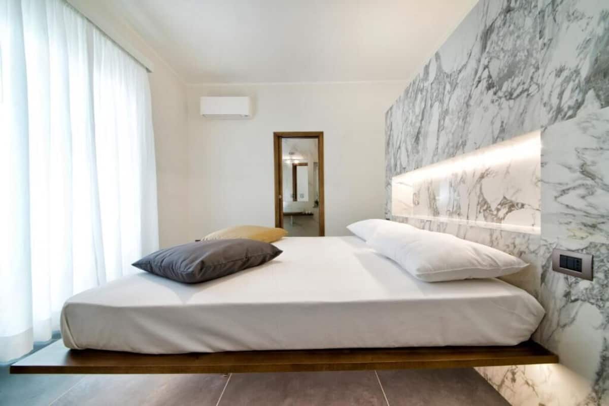 Una camera da letto moderna con un letto, una lampada a parete e uno specchio.