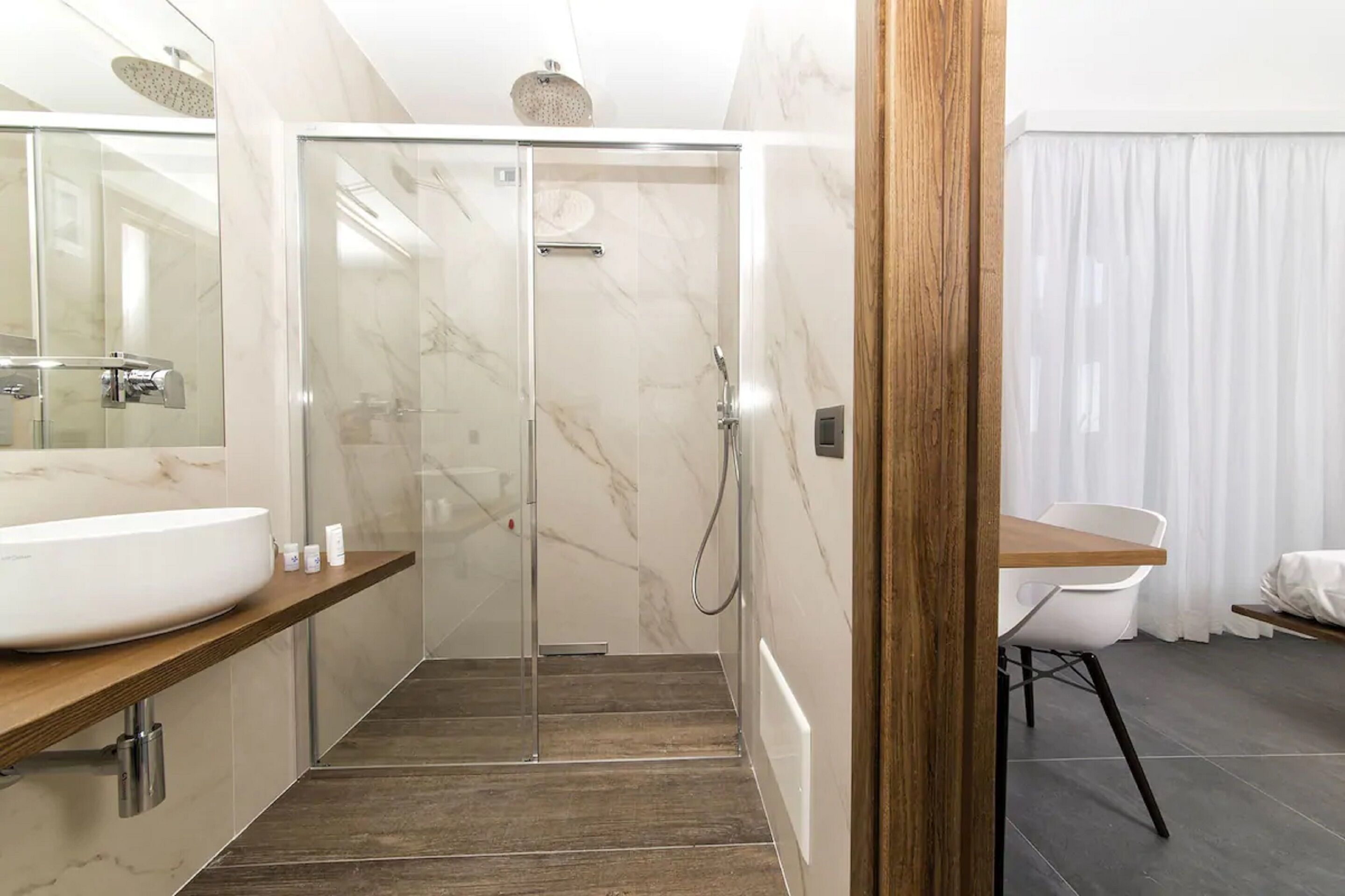 A modern bathroom with a glass-enclosed shower, a wooden vanity, and a white sink.
