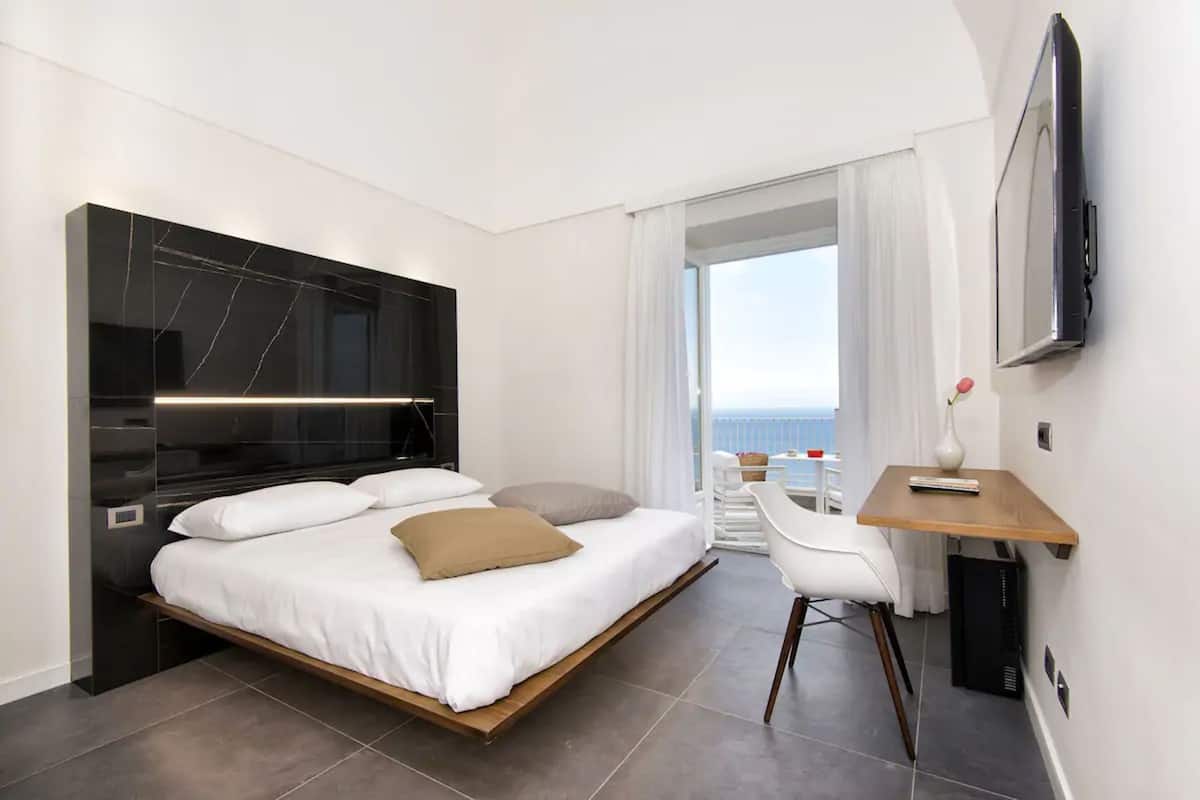 Una camera d'albergo moderna con un letto, una scrivania e un televisore.