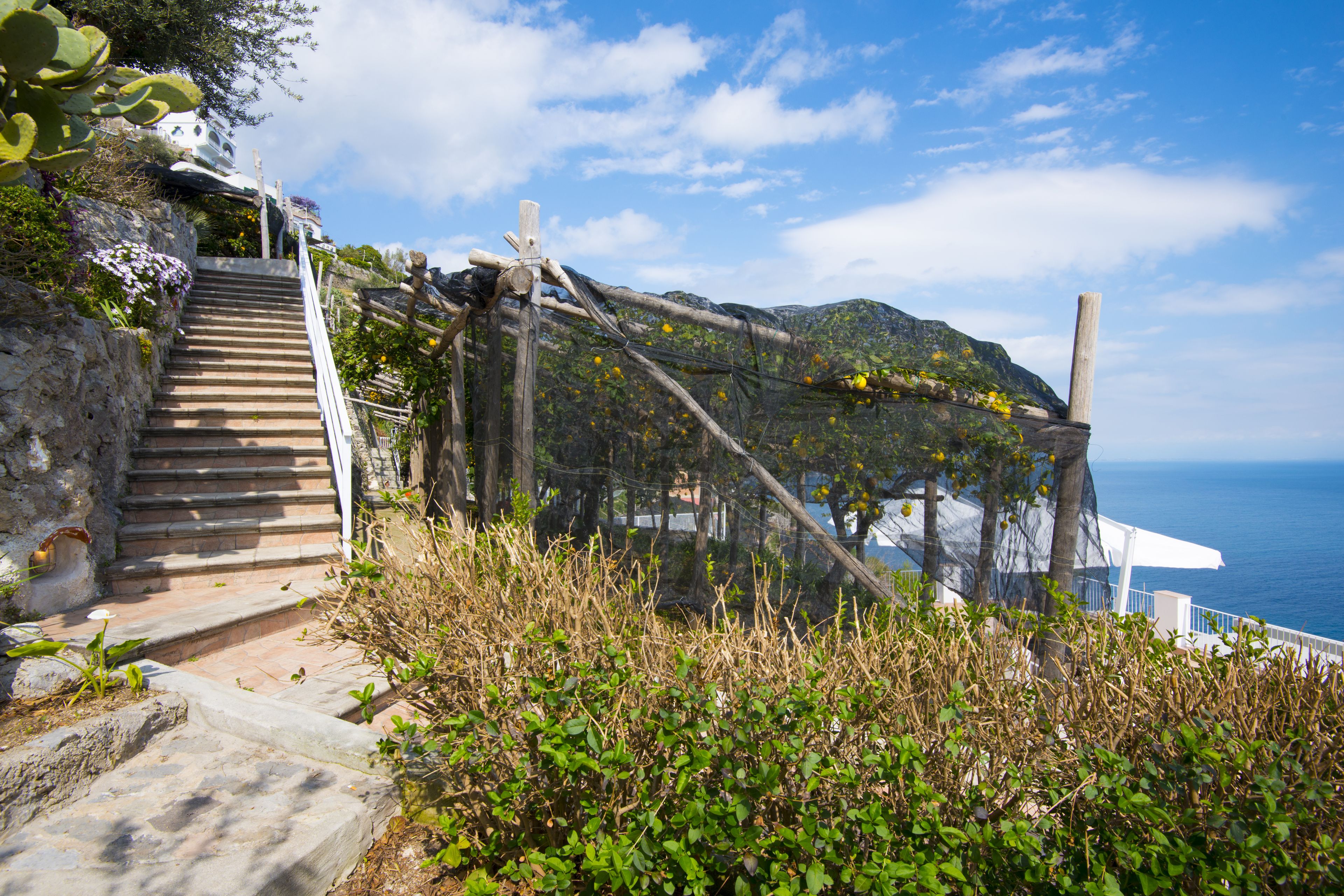 A staircase leading up a rocky hillside with a view of the sea.